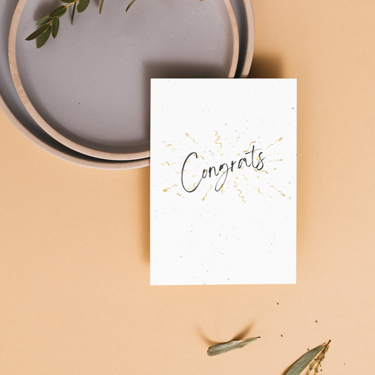White card with 'Congrats' text on top of gold streamers