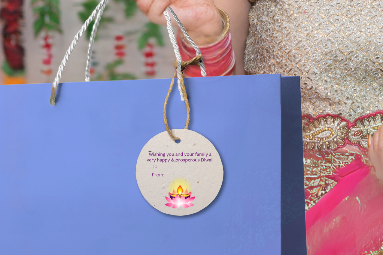 Woman holding a blue gift bag with a decorative Diwali gift tag against a colorful background