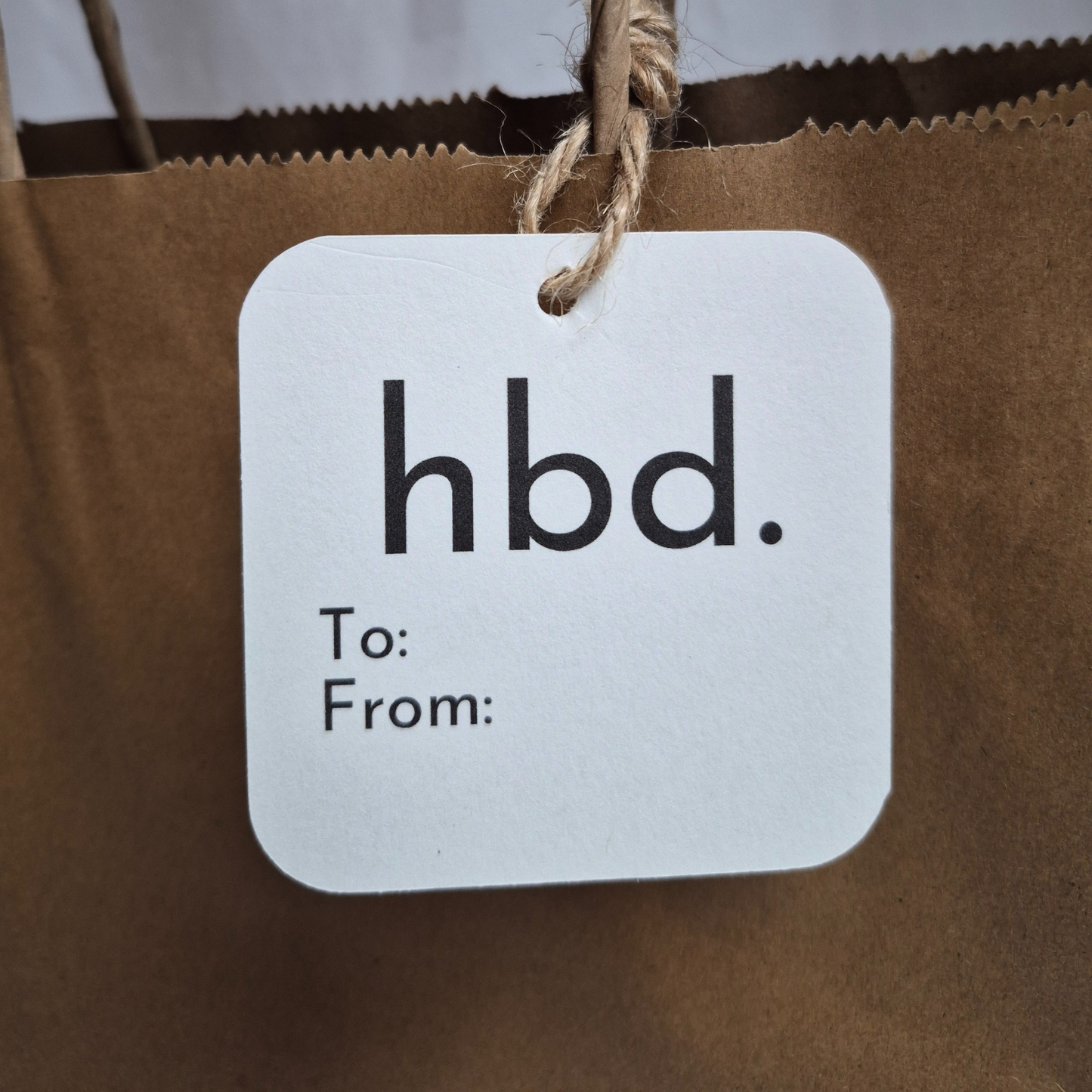 White tag with 'hbd.' text on a brown paper bag