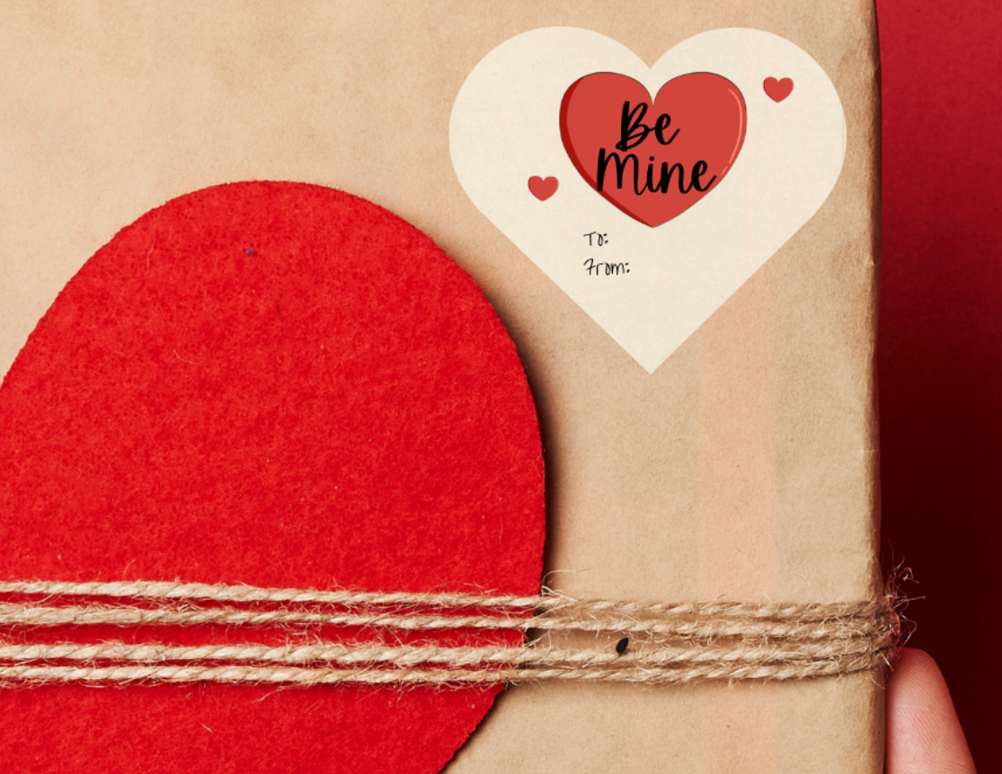 Heart shaped Gift sticker label for Valentine's day, with hearts and inside the large heart there is 'Be mine' text. The heart shaped sticker label is placed on a Gift box with red heart design held against a red background