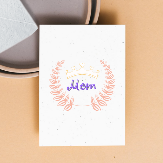 front of card with a pick crest inside the crest is "mom" written in whimsical purple font with grey outline. On top of the word "mom" is a delicate crown with heart ornaments