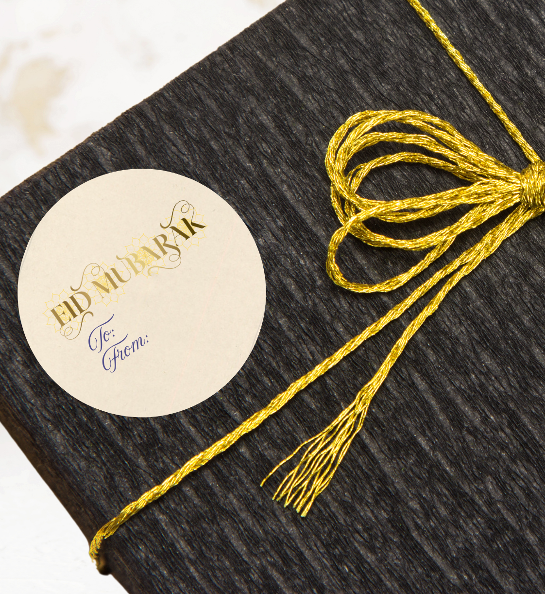 Black gift box with a yellow ribbon and a gift sticker label with 'Eid Mubarak' text