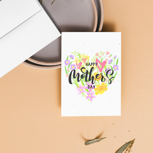 Mother's day greeting card with 'Happy Mother's Day' text and floral design in the shape of a heart as a background on a beige surface.