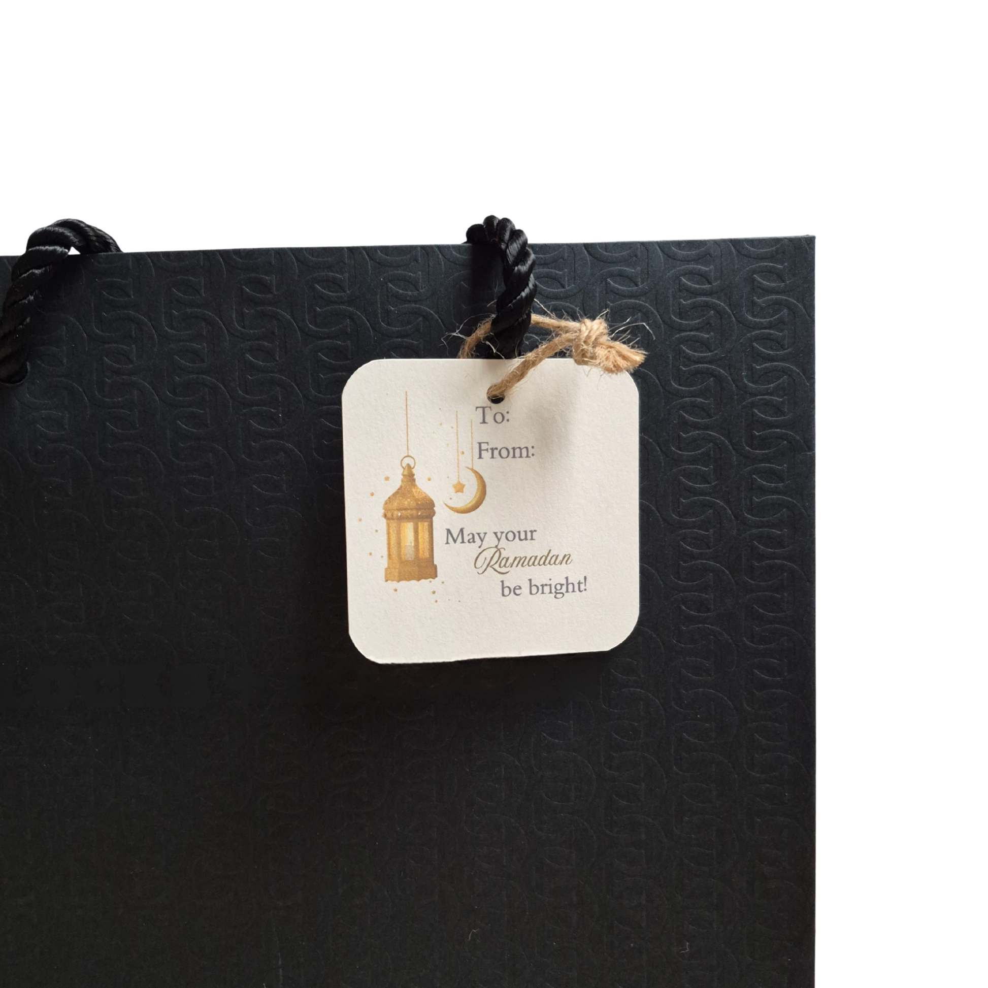 Black gift bag with a decorative gift tag featuring 'May your Ramadan be bright' text