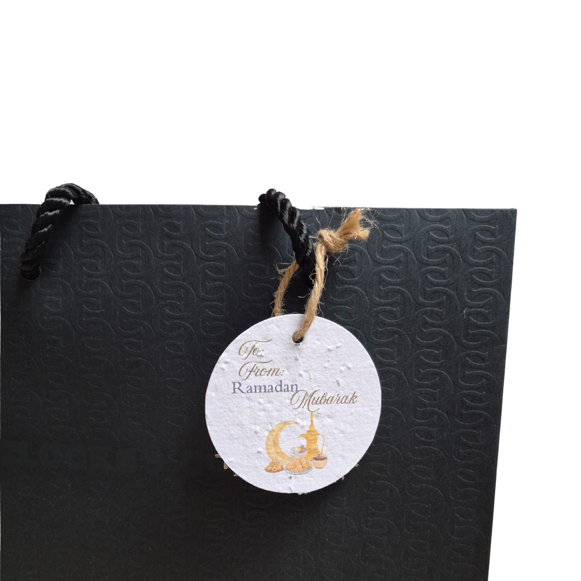 Black gift bag with a seed paper gift tag featuring 'Ramadan Mubarak' text and gold design.