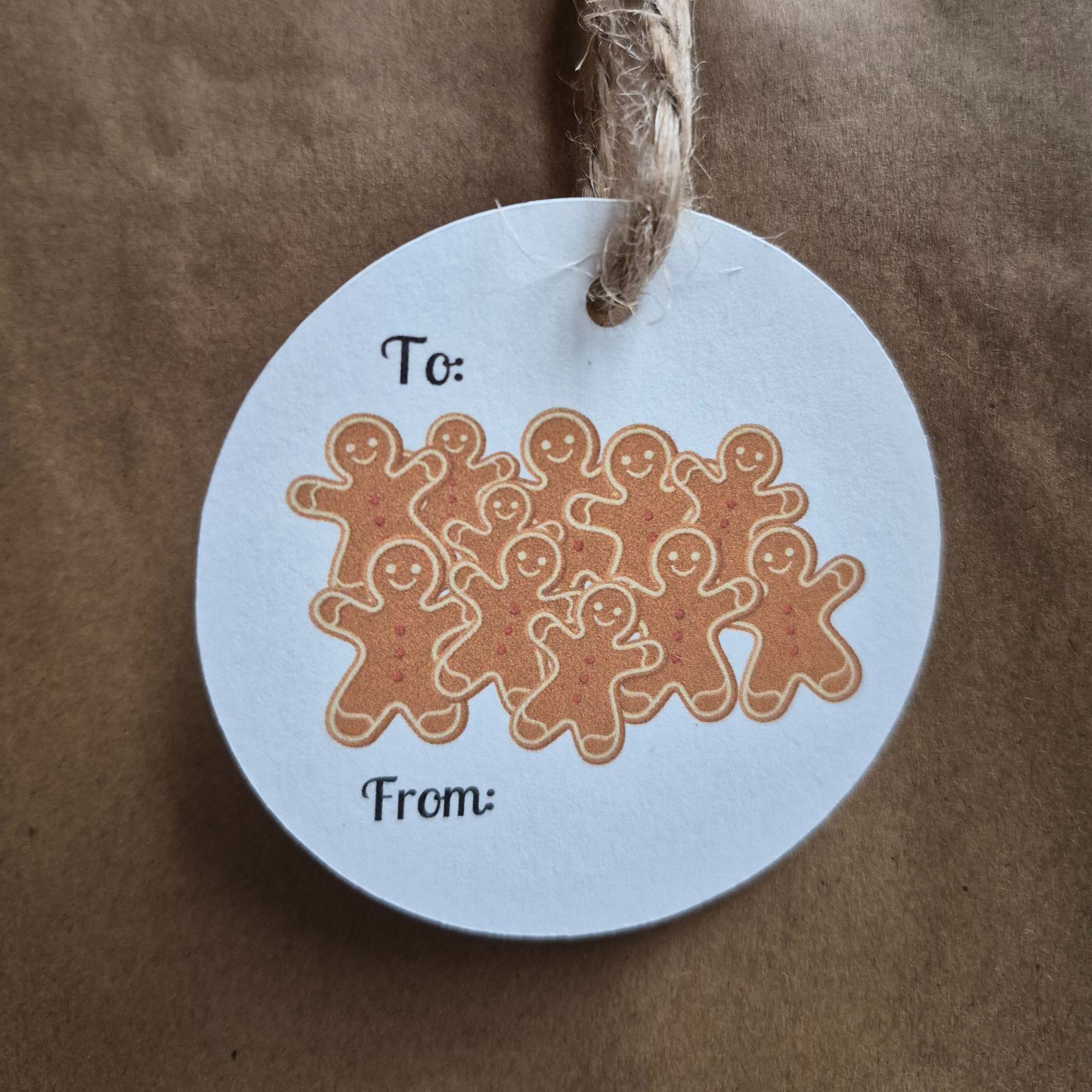 Round Recycled paper Christmas gift tag with gingerbread men design on a brown paper bag background