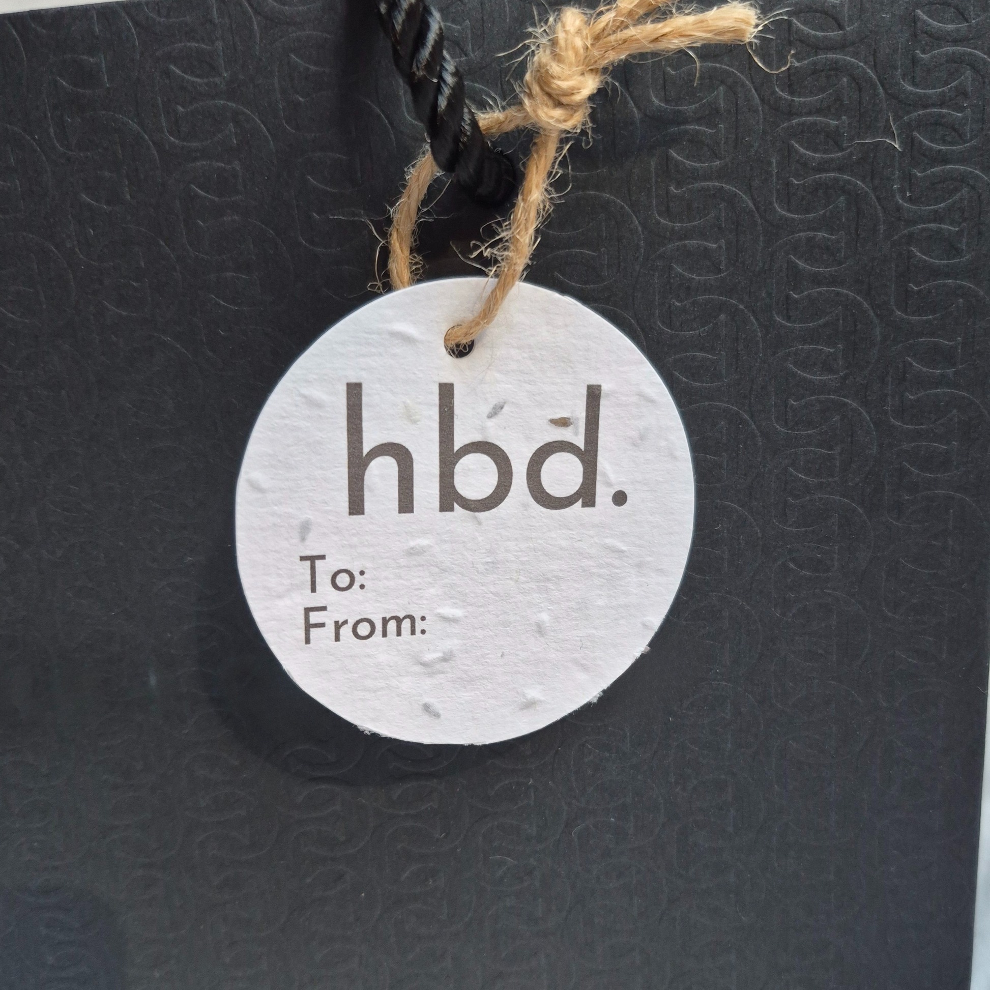 Round BIrthday gift tag  made of seed paper with 'hbd.' text minimalist design
