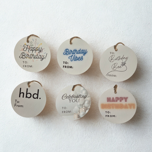 Set of six round birthday gift tags with various messages on a white background