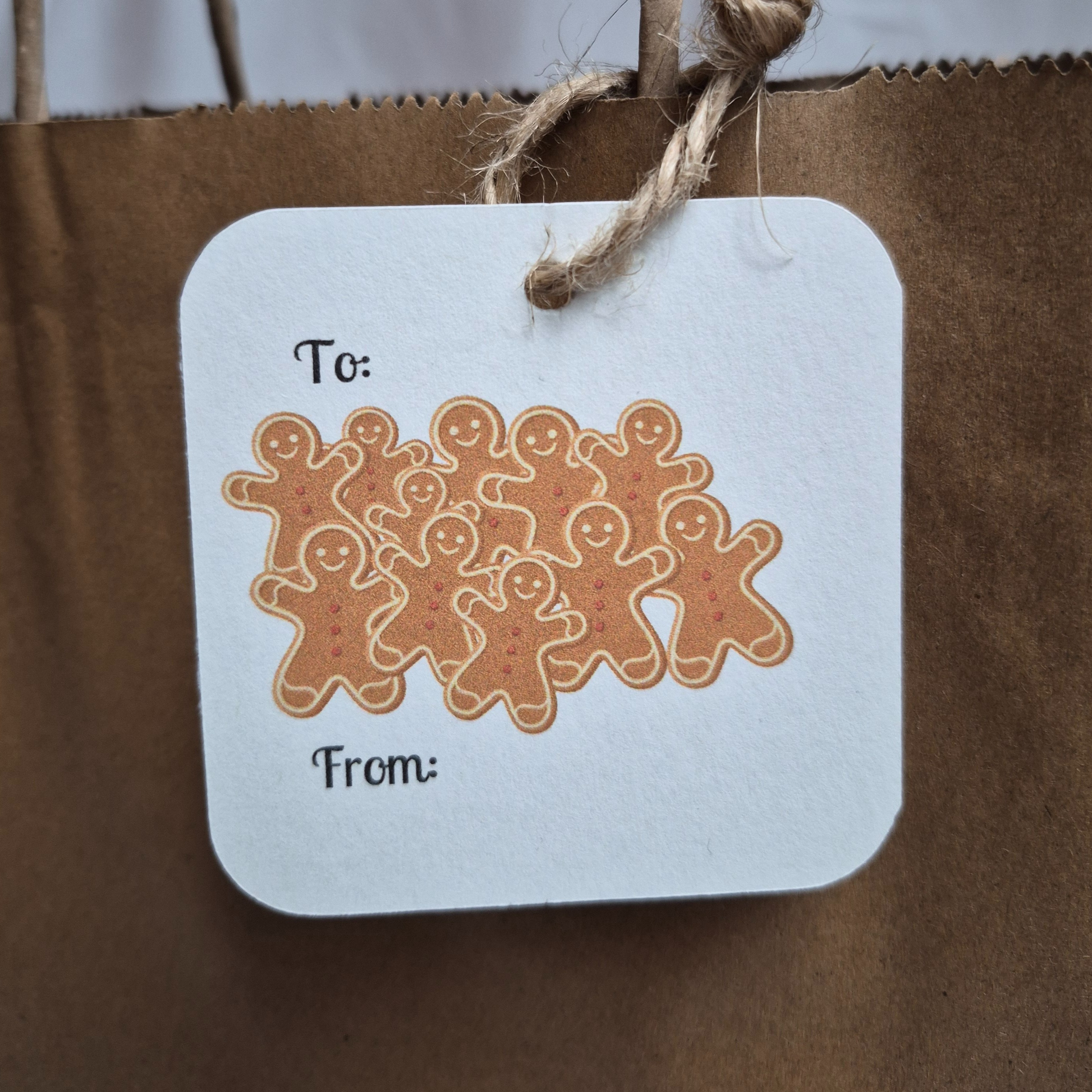 Square recycled paper Christmas gift tag with gingerbread men design on a brown paper bag