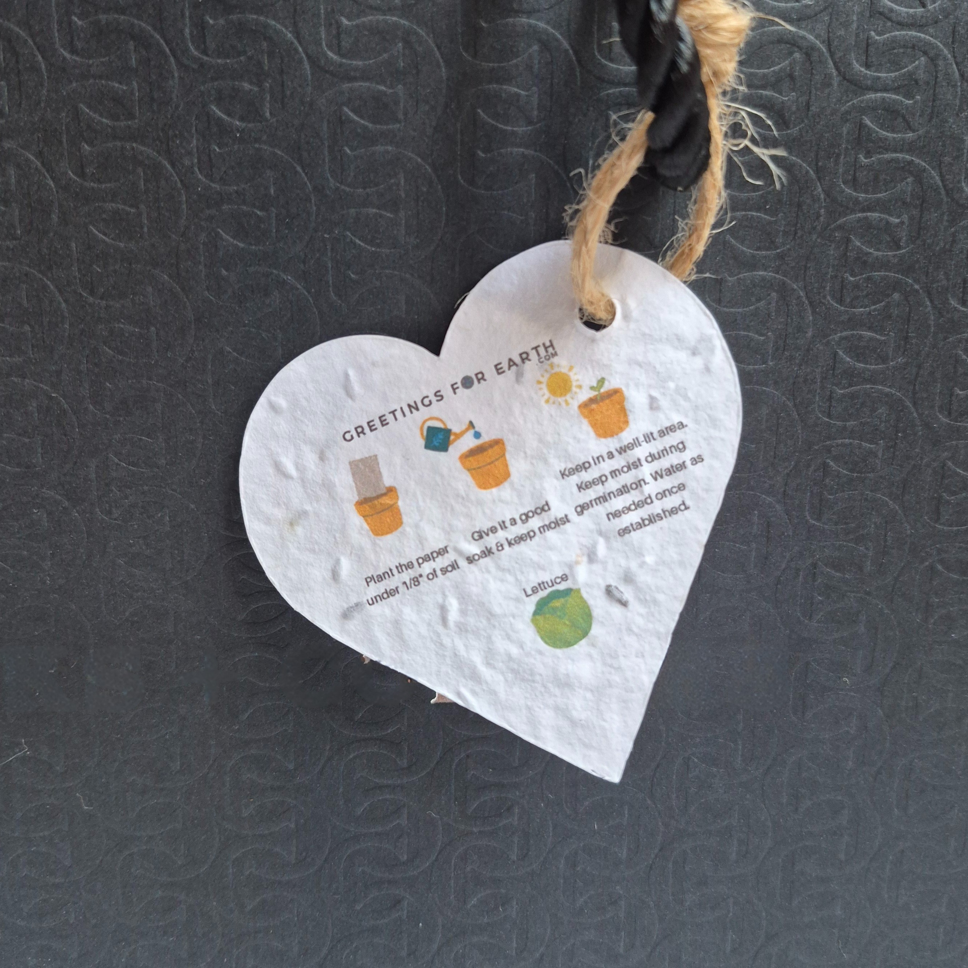 Back of Heart-shaped seed paper tag with planting instructions.  Hanging from a black bag.