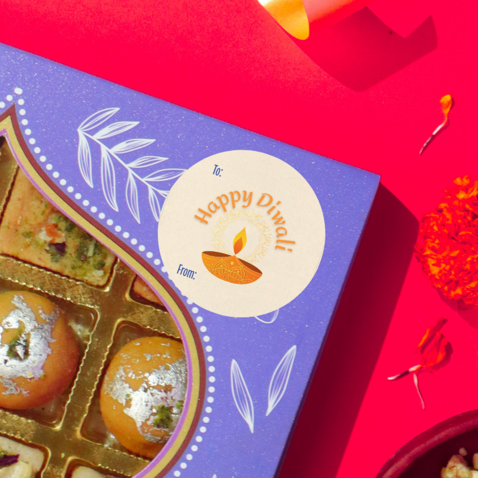 Diwali gift sticker, round, made from compostable sugarcane, with 'Happy Diwali' text and diya illustration. The sticker label is placed on a gift box of Diwali sweets on a red background