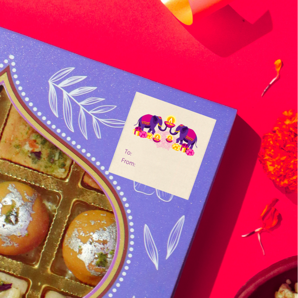 Diwali gift sticker, square, made from compostable sugarcane, with elephants and diyas illustration. The sticker label is placed on a gift box of Diwali sweets on a red background