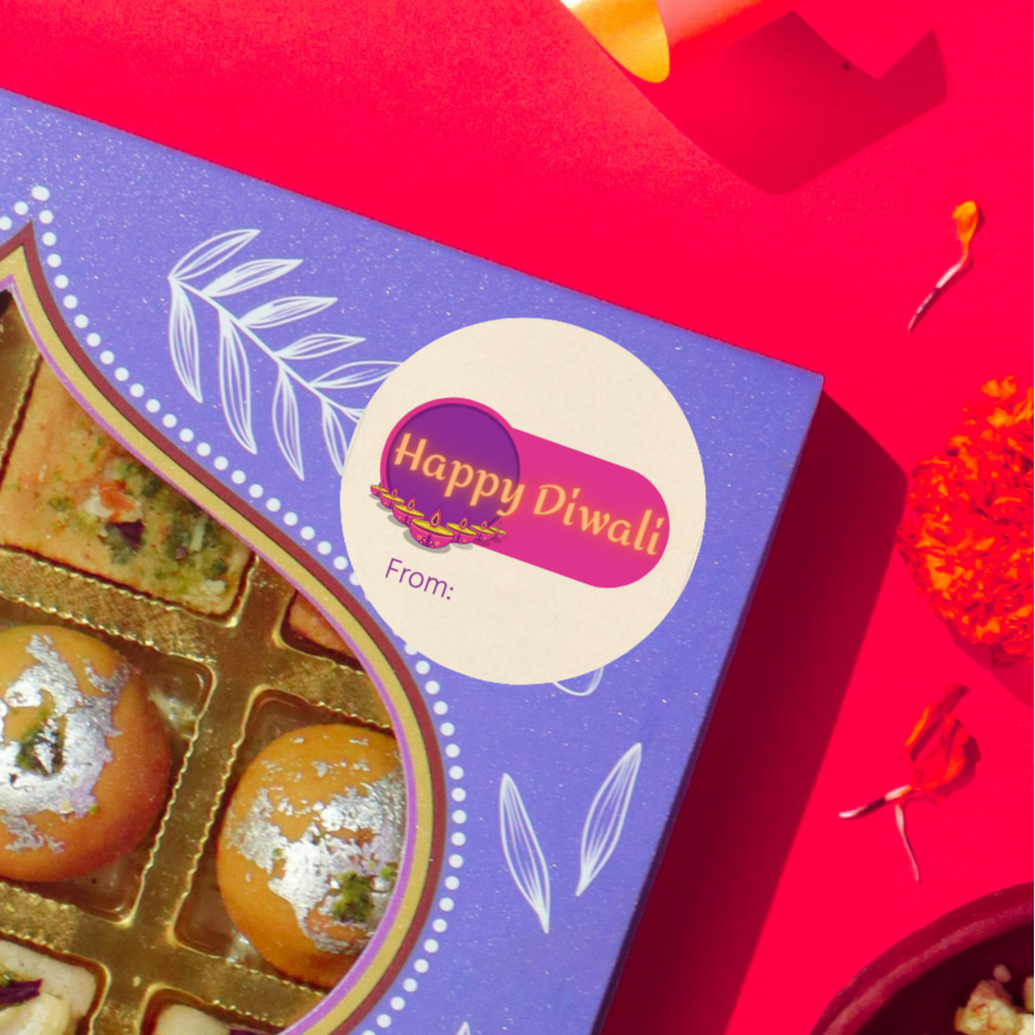 Diwali gift sticker, round, made from compostable sugarcane, with 'Happy Diwali' text and diyas in a v-formation illustration. The sticker label is placed on a gift box of Diwali sweets on a red background