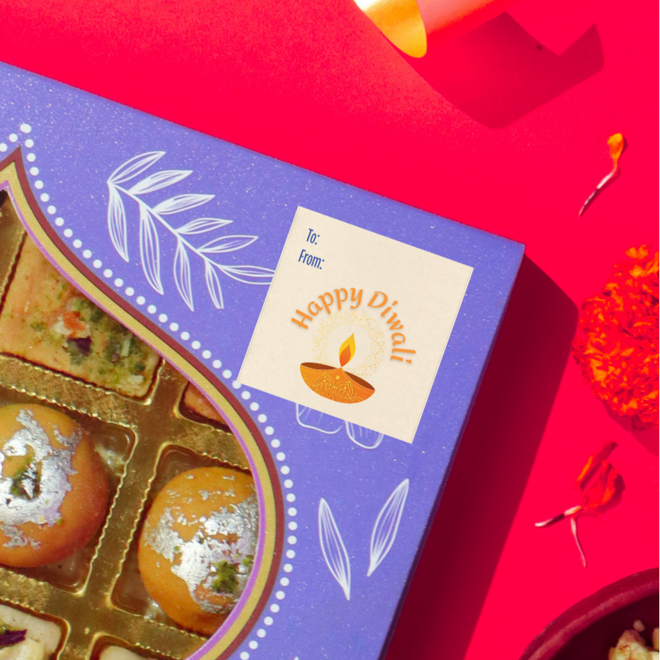 Diwali gift sticker, square, made from compostable sugarcane, with 'Happy Diwali' text and diya illustration. The sticker label is placed on a gift box of Diwali sweets on a red background