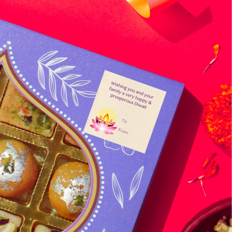 Diwali gift sticker, square, made from compostable sugarcane, with 'wishing you and your family a happy & prosperous Diwali' text and lotus illustration. The sticker label is placed on a gift box of Diwali sweets on a red background