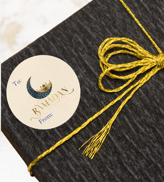 Dark textured box with a gold ribbon and a 'Happy Ramadan 'Moon and Mosque gift sticker on a light background