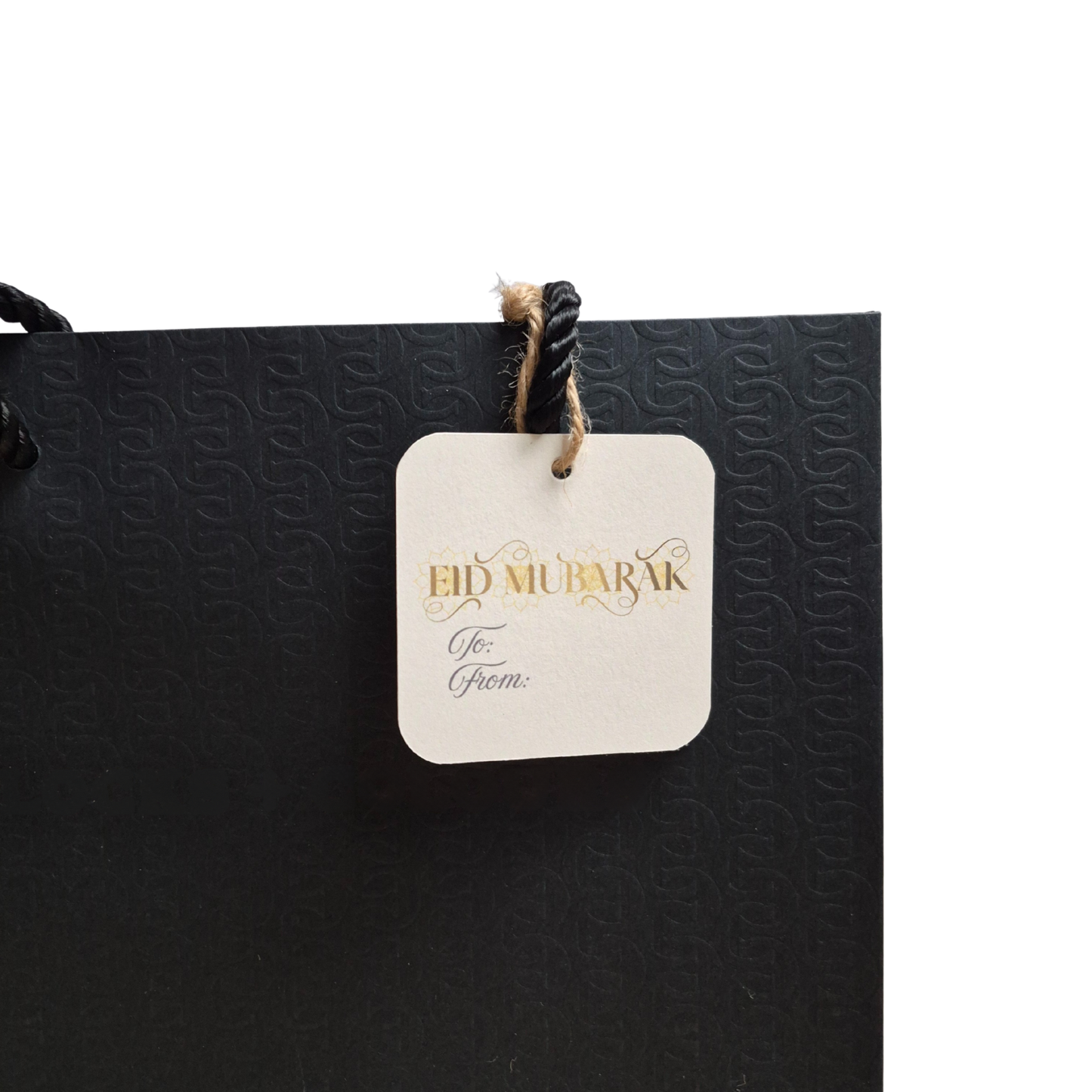  'Eid Mubarak'  text on a recycled paper gift tag that is eco-friendly. Hanging on a black bag.