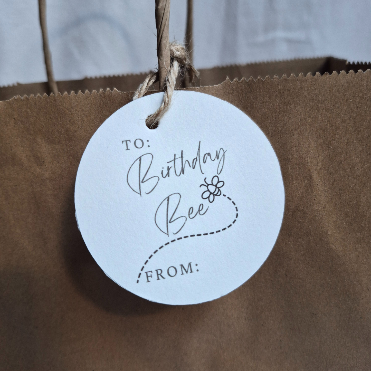 Round Birthday gift tag with 'Birthday Bee' text and a bee illustration on a brown paper bag.