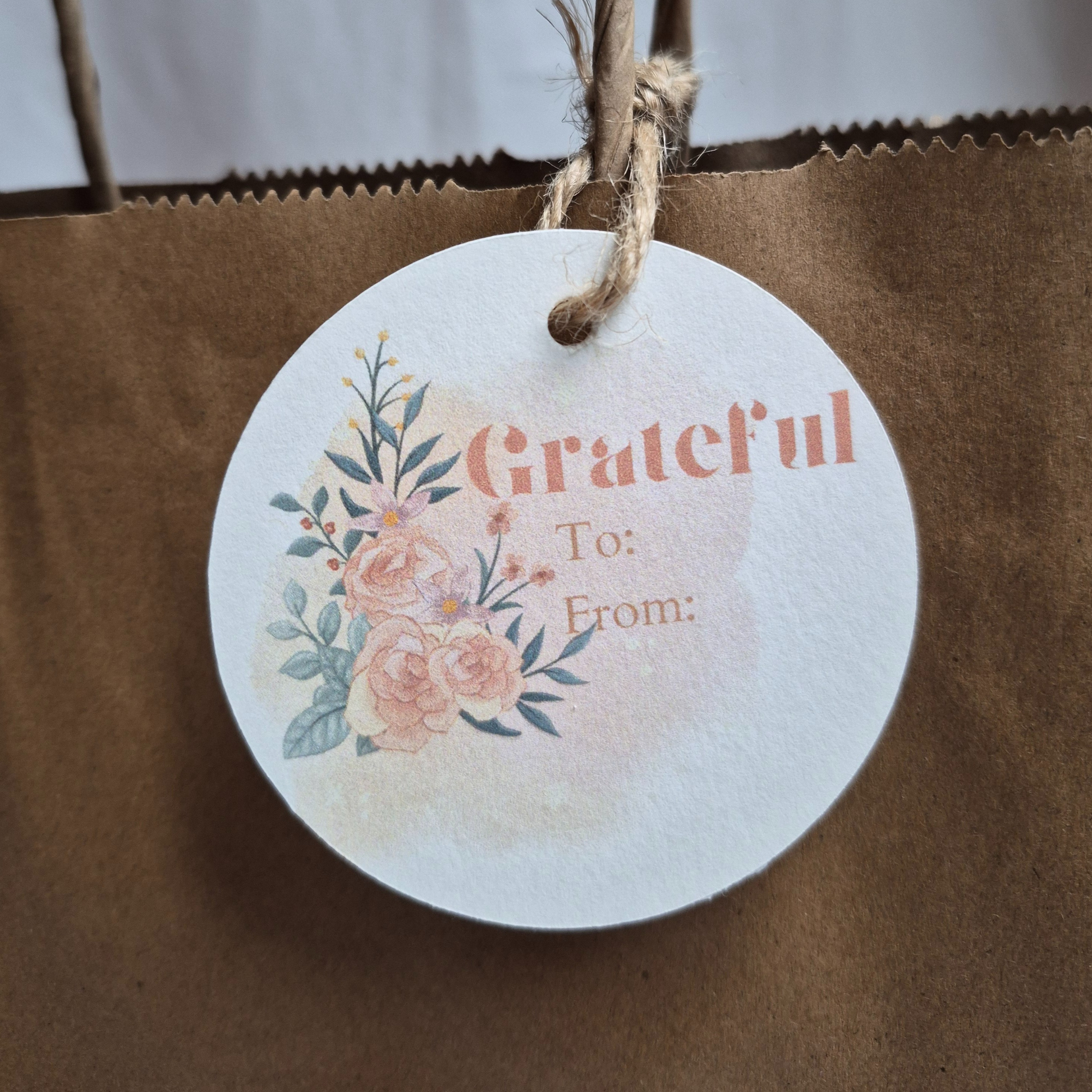 Round Thank you gift tag made of recycled paper with floral design and 'Grateful To: From:' text on a brown paper bag.