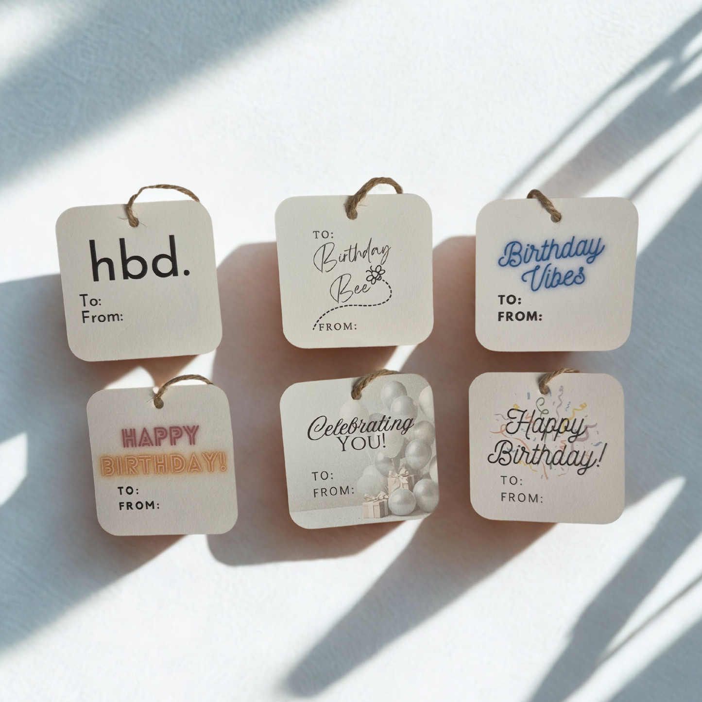 Set of six square birthday gift tags made of recycled paper with various messages on a light background