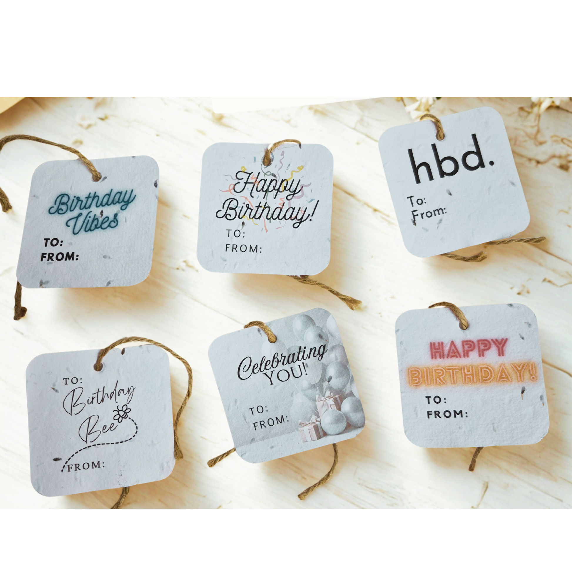 Set of six square birthday gift tags made of seed paper with various messages on a light background