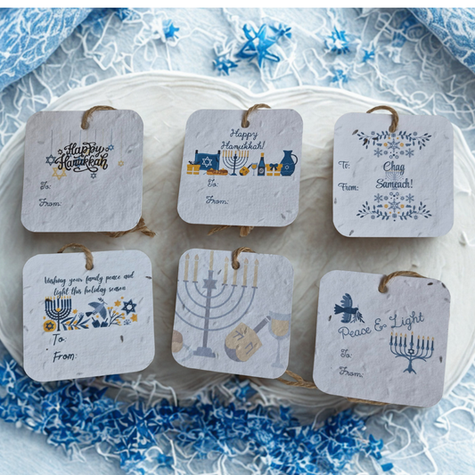 Set of  six Hanukkah-themed gift tags made of seed paper, on a decorative plate with blue and white floral pattern.