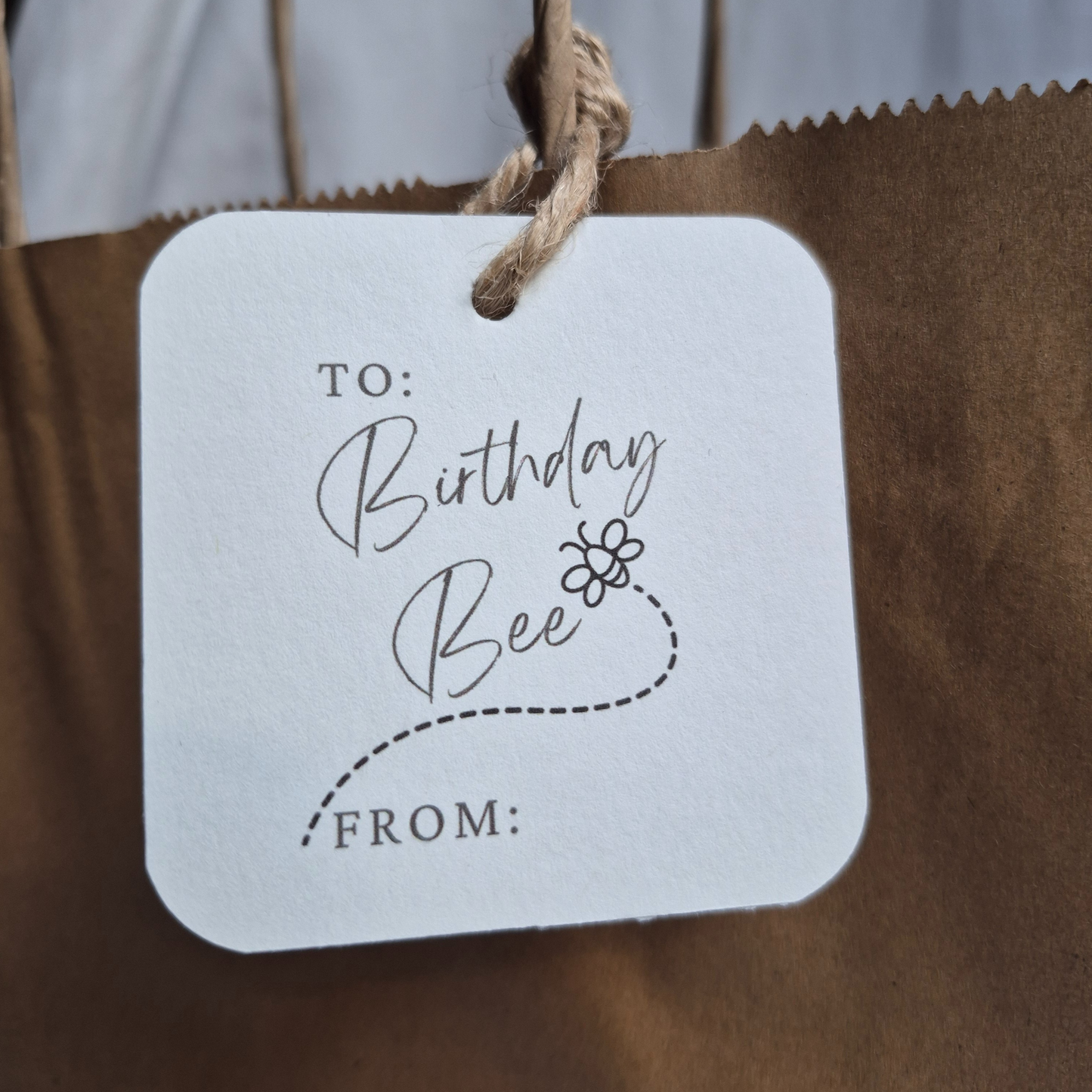 Square Birthday gift tag with 'Birthday Bee' text  and a bee illustration on a brown paper bag.