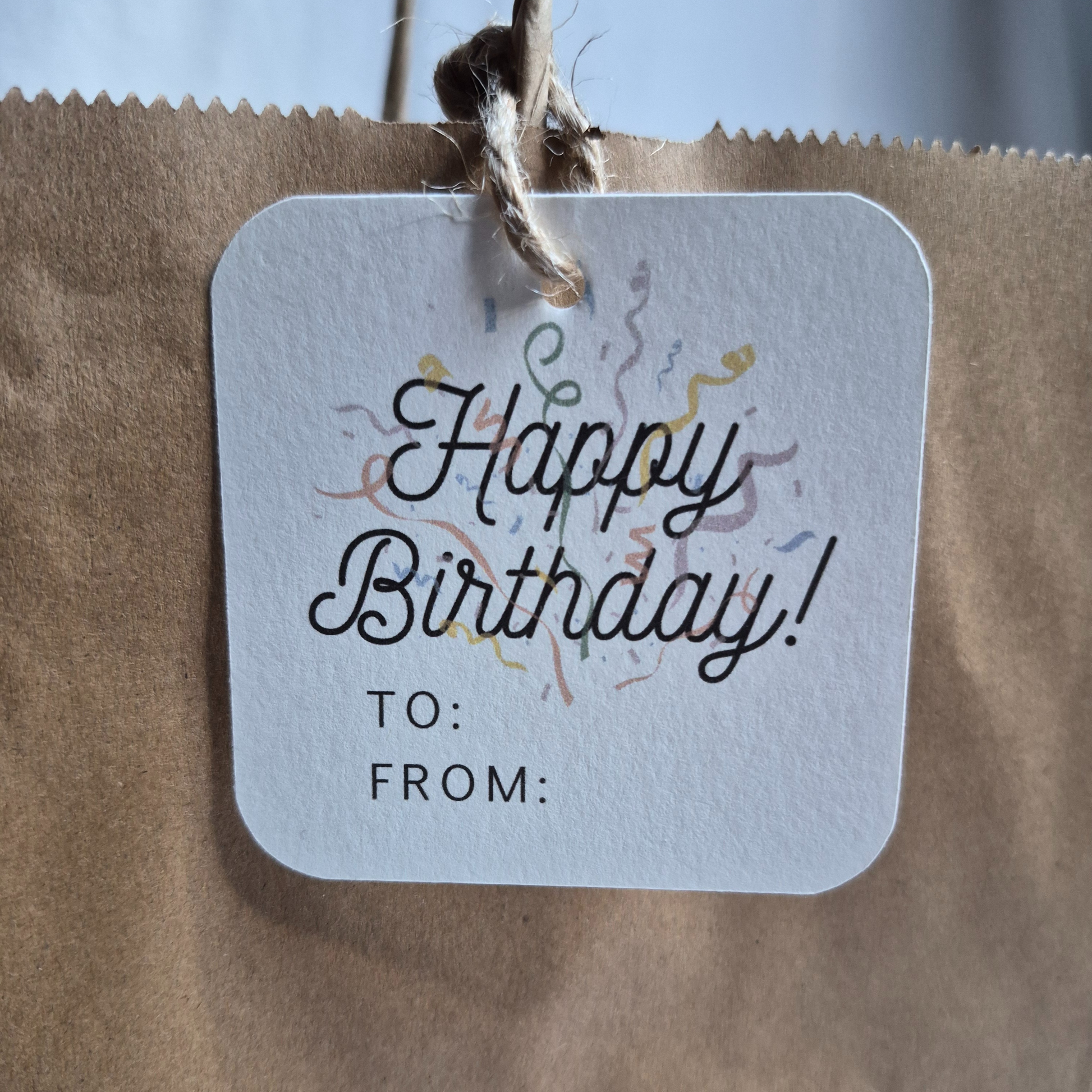 Square Birthday gift tag with 'Happy Birthday!' text and confetti on a brown paper bag