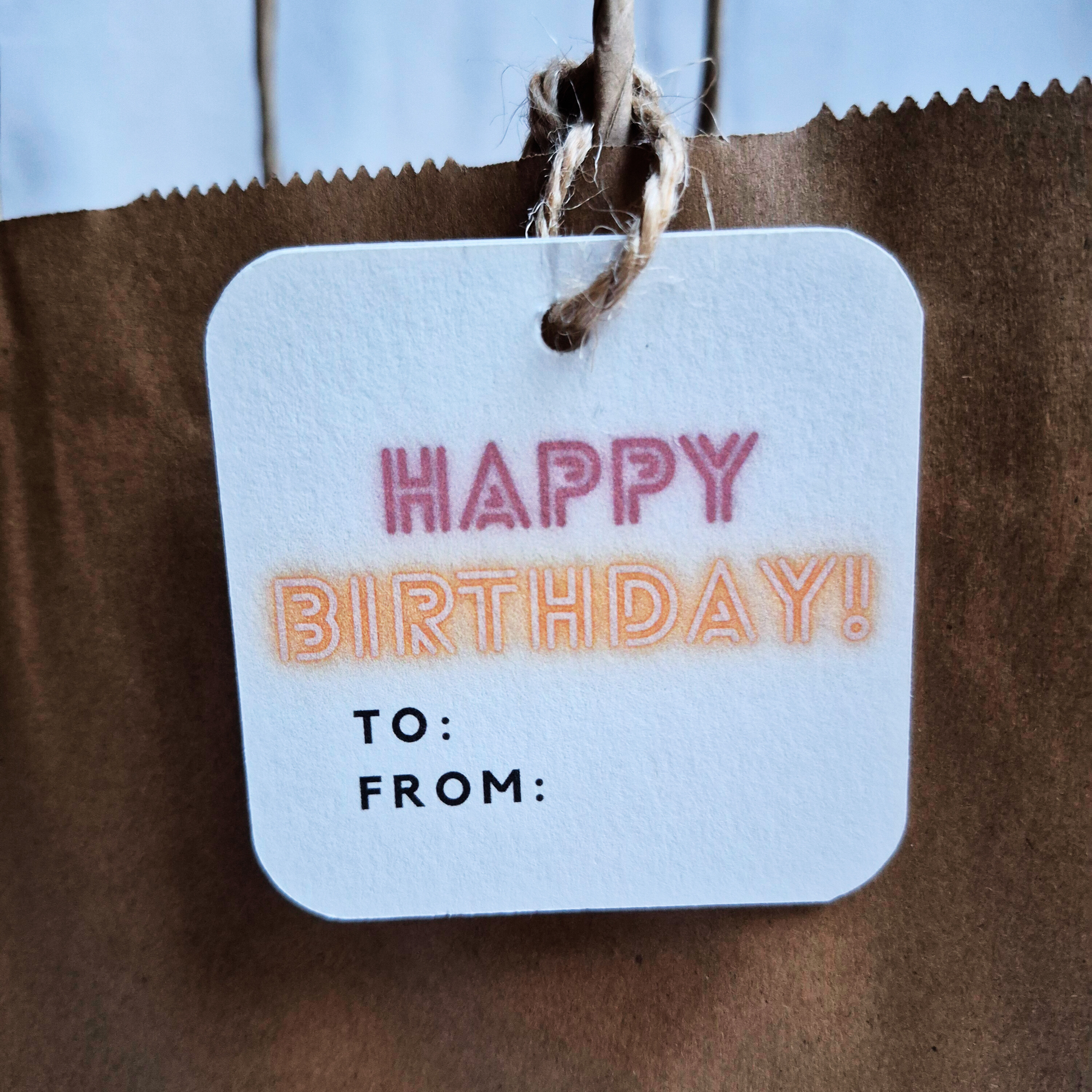 Square Birthday gift tag with 'Happy Birthday!' in neon text on a brown paper bag